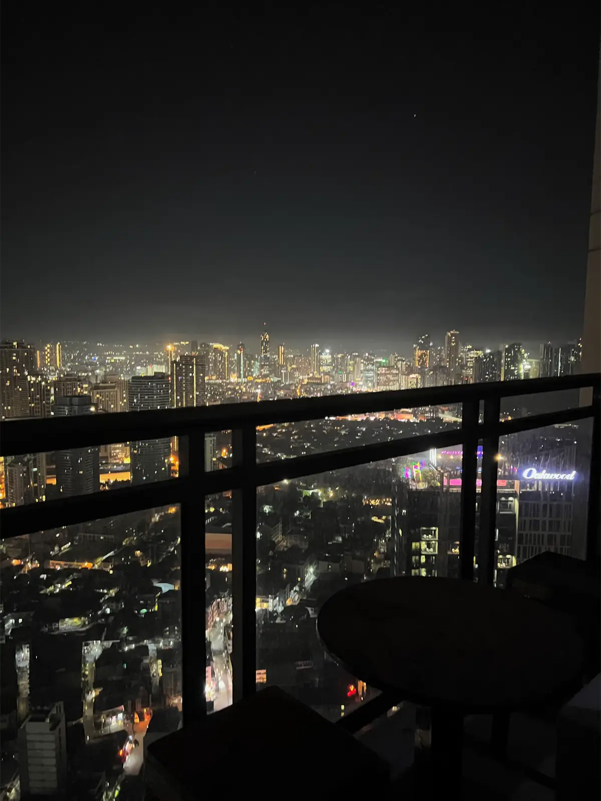 Makati city lights beyond the private balcony railing and table.
